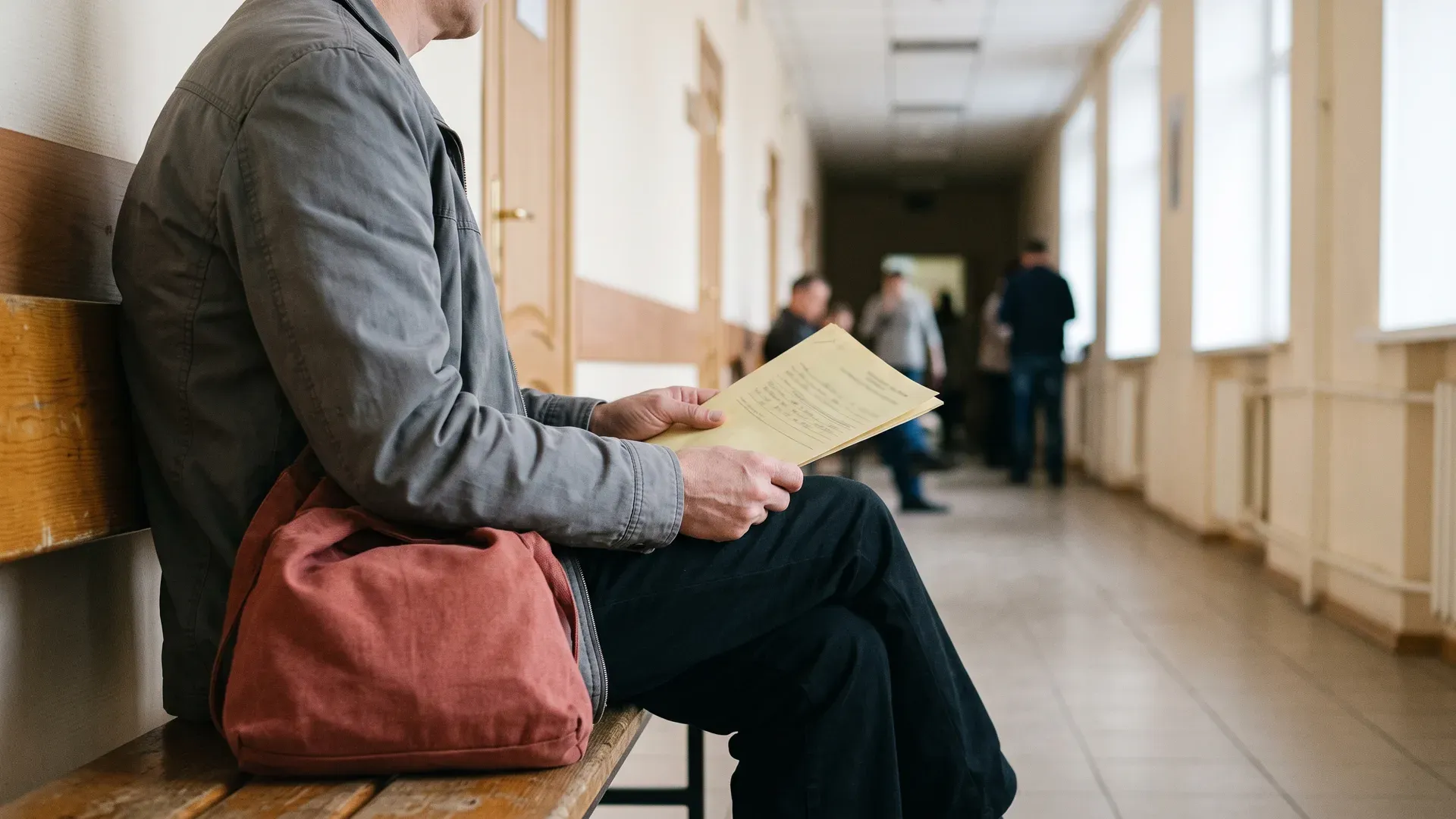 мужчина сидит в коридоре с документами в руках